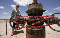 Ashley Williams Watt looks at an abandoned well wrapped with locks and chains on her ranch, Friday, July 9, 2021, near Crane, Texas. Some of her wells are leaking chemicals such as benzene, a known carcinogen, into fields and drinking water. (AP Photo/Eric Gay)