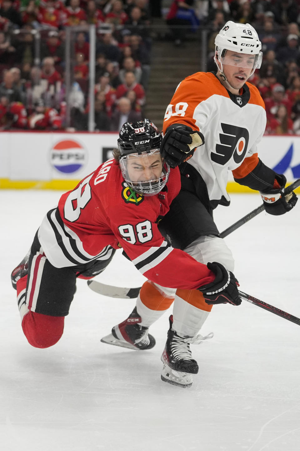 Chicago Blackhawks center Connor Bedard, left, trips over Philadelphia Flyers center Morgan Frost during the second period of an NHL hockey game Wednesday, Feb. 21, 2024, in Chicago. (AP Photo/Erin Hooley)