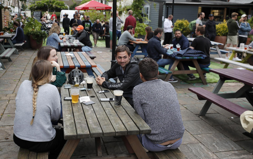 People enjoy their drinks at The Black Lion pub in London, Saturday, July 4, 2020. England is embarking on perhaps its biggest lockdown easing yet as pubs and restaurants have the right to reopen for the first time in more than three months. In addition to the reopening of much of the hospitality sector, couples can tie the knot once again, while many of those who have had enough of their lockdown hair can finally get a trim. (AP Photo/Frank Augstein)