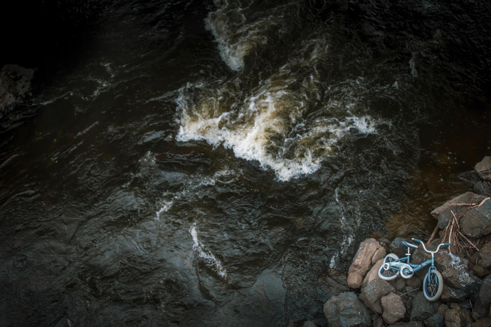 A kid's bike lies beside the shore of the Winooski River which runs through Montpelier, Vt., July 3, 2024. The river has flooded the state's capital in 2023 causing massive damages. A year after catastrophic flooding inundated parts of Vermont, some homeowners are still in the throes of recovery. (AP Photo/ Dmitry Belyakov)