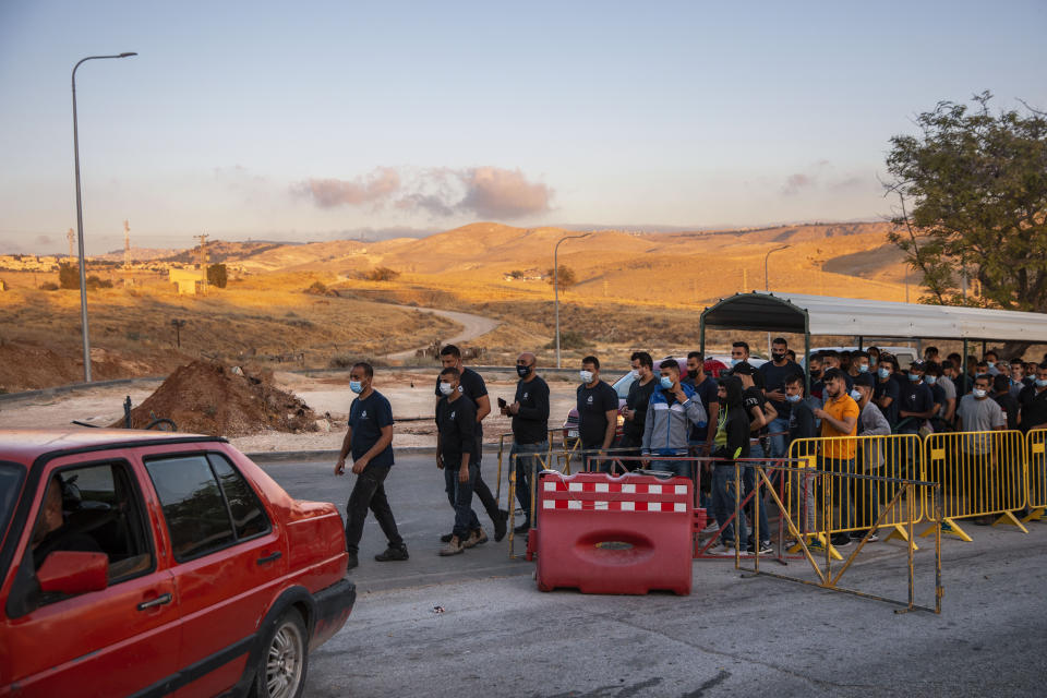 Palestinians laborers line up to cross a checkpoint at the entrance to the Israeli settlement of Maale Adumim, near Jerusalem, Tuesday, June 30, 2020. Israeli Prime Minister Benjamin Netanyahu appears determined to carry out his pledge to begin annexing parts of the occupied West Bank, possibly as soon as Wednesday. (AP Photo/Oded Balilty)