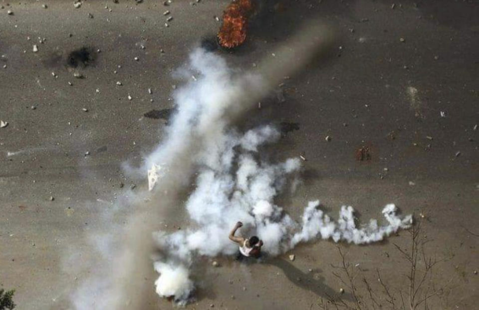 In this Friday, Dec. 21, 2018 handout photo provided a Sudanese activist, a protester stands in tear gas during clashes with security forces in Khartoum, Sudan. The protest was one in a series of anti-government protests across Sudan, initially sparked by rising prices and shortages. (Sudanese Activist via AP)