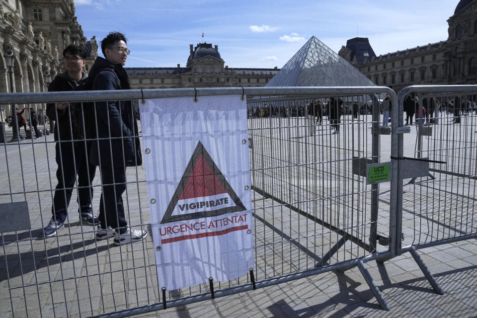 Tourist stand by a sign alerting on France's highest security level at the Louvre museum, Monday, March 25, 2024 in Paris. France's government increased its security alert posture to the highest level Sunday March 24, 2024 after the deadly attack at a Russian concert hall and the Islamic State's claim of responsibility. (AP Photo/Michel Euler)