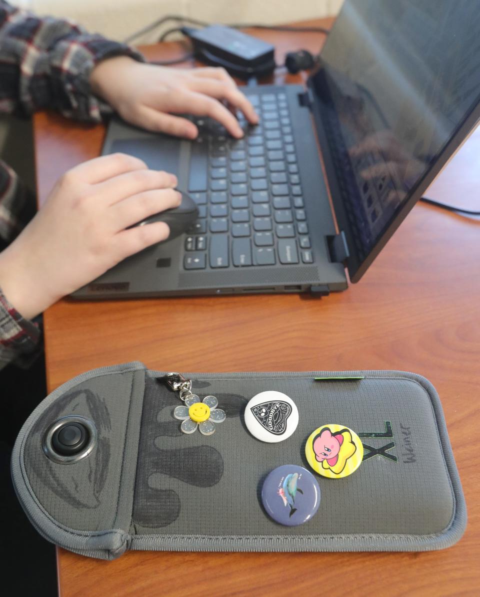 A locked Yondr pouch rests next to a student working on a computer in an Akron, Ohio school. Brockton is bringing these Yondr pouches to the high school next year, where all students will be required to lock up their phones during the school day.