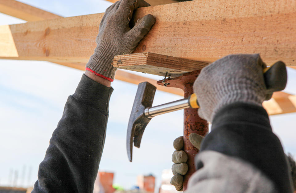 A person hammering nails in a house