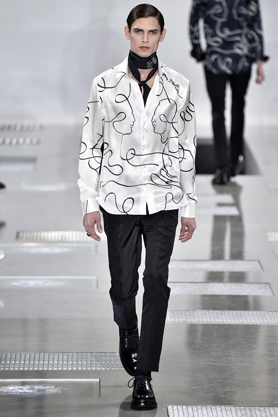 <p>Model wears a silk white shirt with Jean Cocteau-inspired illustrations, sleek black trousers, and a chic skinny neck scarf. (Photo: Getty Images) </p>
