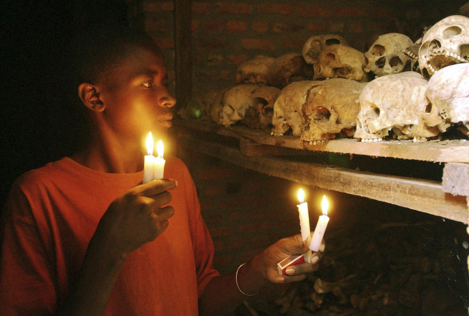 FILE - In this April 6, 2004 file photo, Apollan Odetta, a survivor from the 1994 Rwandan Genocide light candles at a mass grave in Nyamata, Rwanda. Two decades after the Rwandan genocide, France is finally opening what critics called its blind eye to justice over the killings. On Tuesday Feb. 4, 2014, a wheelchair-bound Rwandan former intelligence chief appears in Paris court for an expected seven-week trial to face charges of complicity in genocide and complicity in crimes against humanity. (AP Photo/Sayyid Azim, File)