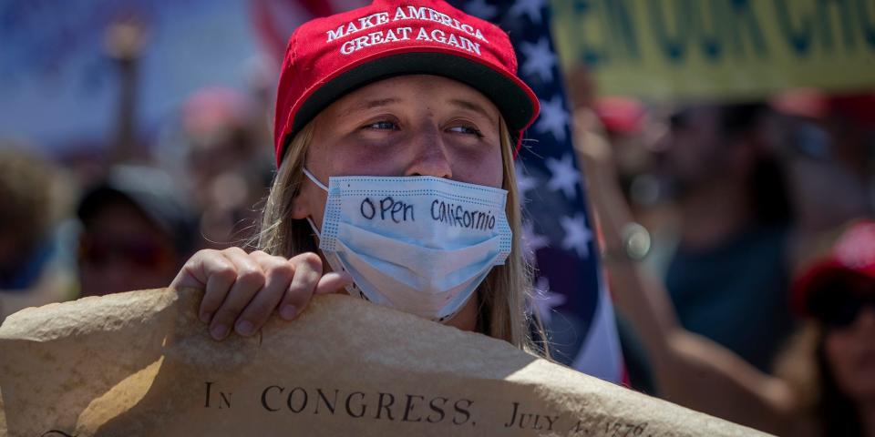 A protester sporting a message on her protective mask and holding the U.S. Constitution poster, sends a message to Gov. Newsom while joining thousands of protesters at the intersection of Main Street and Pacific Coast Highway in the``March to Open California'' to call on Gov. Newsom to re-open the beaches and relax the state's stay-at-home orders under COVID-19 in Huntington Beach, CA, on May 1, 2020