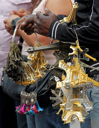 FILE PHOTO: A souvenir vendor sells Eiffel tower models for tourists in front the Eiffel Tower at the Trocadero in Paris, France, July 26, 2011. REUTERS/Eric Gaillard/File Photo