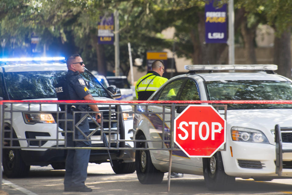 Law enforcement personnel stand with weapons near two LSU police vehicles parked in between the LSUU Student Union and Coates Hall, in New Orleans after the all-clear on a possible armed intruder in Coates Hall, Tuesday, August 20, 2019. (Travis Spradling/The Advocate via AP)