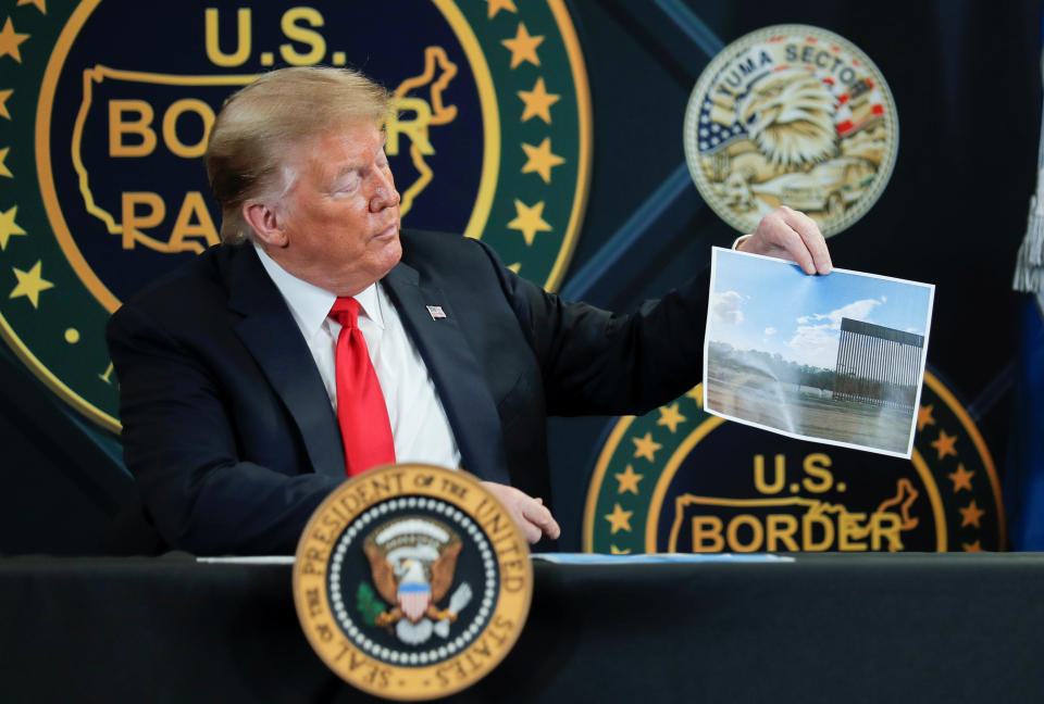 U.S. President Donald Trump holds up a picture of border wall being installed along the U.S.-Mexico border as he participates in a roundtable briefing on border security at the U.S. Border Patrol Yuma Station in Yuma, Arizona, U.S., June 23, 2020. REUTERS/Carlos Barria