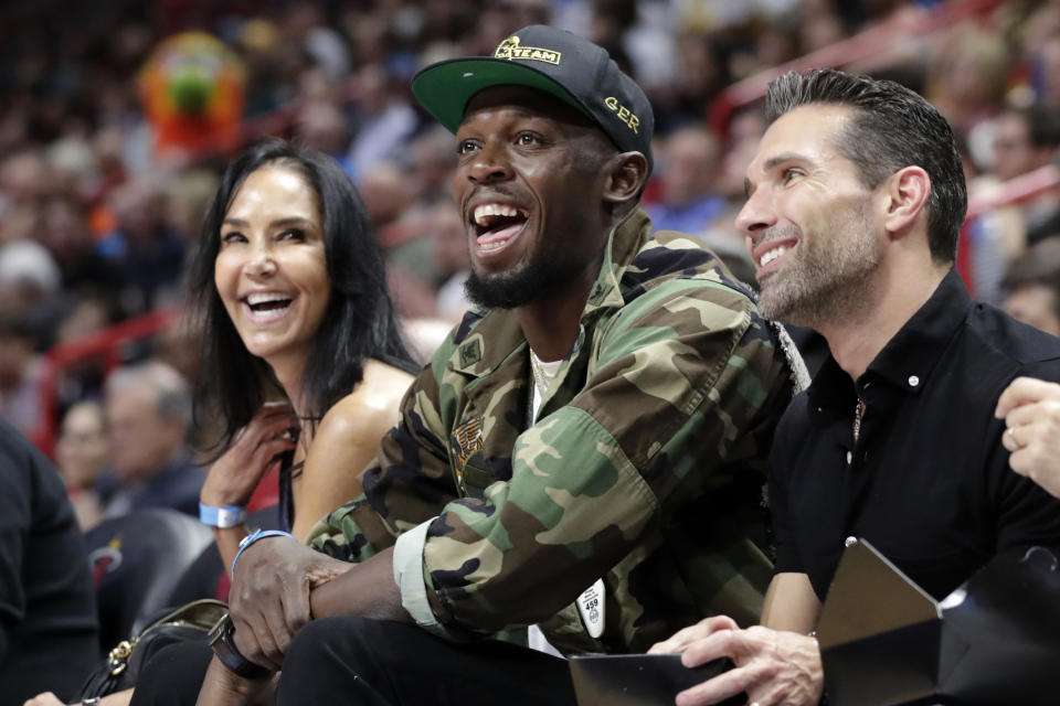 FILE - In this Dec. 13, 2019, file photo, Usain Bolt watches the first half of an NBA basketball game between the Miami Heat and Los Angeles Lakers in Miami. The retired world’s fastest man is not only changing diapers these days, but also distances as he makes a brief comeback for a promotional event.(AP Photo/Lynne Sladky, File)