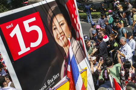 Protest leader Suthep Thaugsuban (R) receives donations from his supporters as he walks past a poster of Thailand's Prime Minister Yingluck Shinawatra, during a march through central Bangkok January 30, 2014. REUTERS/Athit Perawongmetha