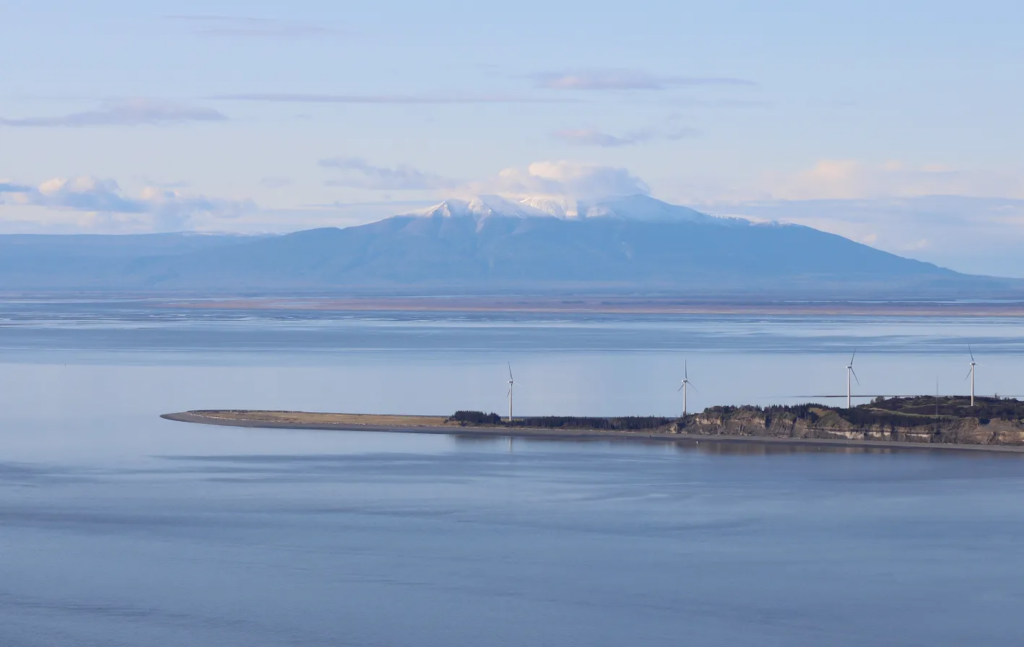 Wind turbines spin at a development at Fire Island, just offshore from Anchorage. Mount Susitna, or Dghelishla, is in the background. (Photo by Nathaniel Herz/Northern Journal)