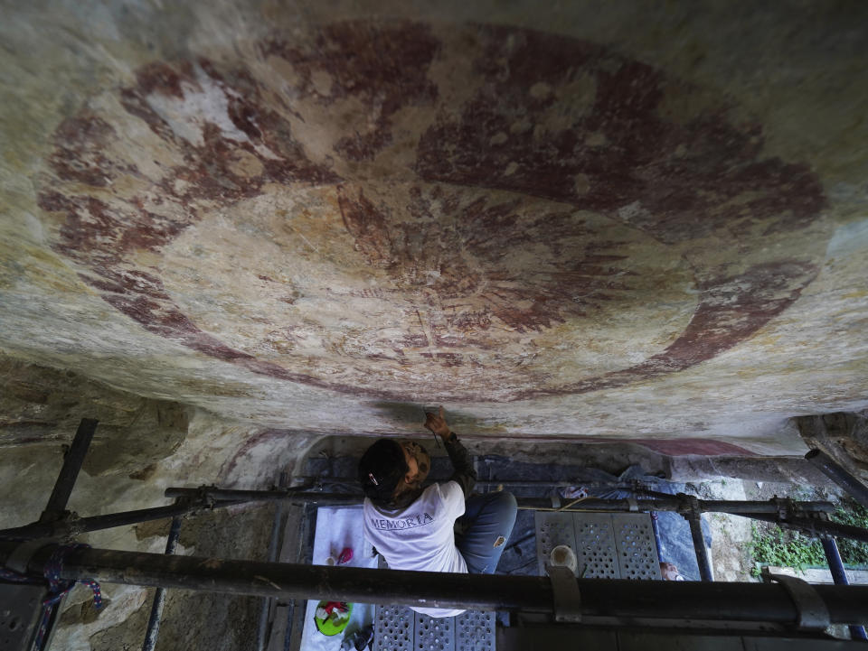 Valeria Lopez restores a mural at the 1550s-era convent convent of Tepoztlan in Morelos state, Mexico, Friday, Oct. 7, 2022. Indigenous symbols were found painted next to Roman Catholic motifs at this convent near Mexico City. (AP Photo/Marco Ugarte)