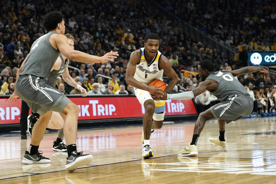 Marquette's Kam Jones (1) drives to the basket between Xavier's Souley Boum (0), Adam Kunkel, and Cesare Edwards during the first half of an NCAA college basketball game Wednesday, Feb. 15, 2023, in Milwaukee. (AP Photo/Aaron Gash)