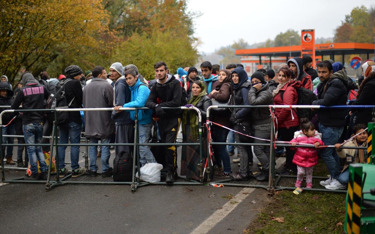 Migrants wait behind a barrier at the border between Austria and Germany in Achleiten, Austria, Thursday, Oct. 29, 2015. Thousands of people are trying to reach central and northern Europe via the Balkans but often have to wait for days. (AP Photo/Kerstin Joensson) -  Kerstin Joensson/AP