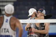 Jacob Gibb, center, of the United States, hugs teammate Tri Bourne after winning a men's beach volleyball match against Italy at the 2020 Summer Olympics, Sunday, July 25, 2021, in Tokyo, Japan. (AP Photo/Felipe Dana)