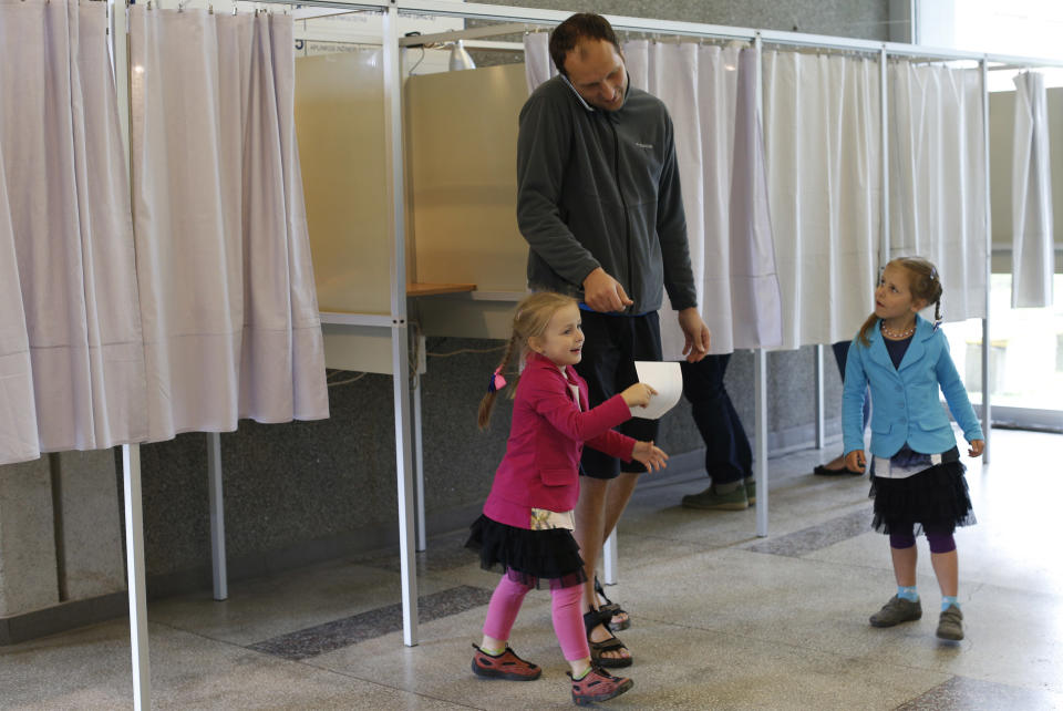 A Lithuanian family leave a voting booth during the first round of voting in presidential elections in Vilnius, Lithuania, Sunday May 11, 2014. Polls opened Sunday for the presidential election in Lithuania, where tough-talking incumbent Dalia Grybauskaite is widely expected to be re-elected for a second term. (AP Photo/Mindaugas Kulbis)