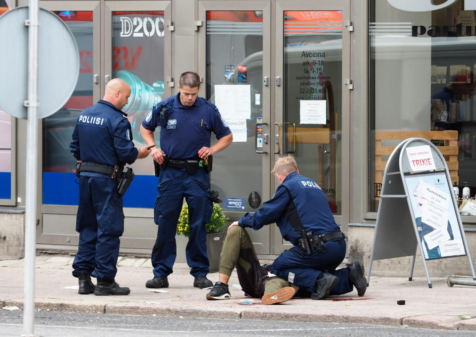 <p>Police officers stand next to a person lying on the pavement in the Finnish city of Turku where several people were stabbed on Aug. 18, 2017. (Kirsi Kanerva/AFP/Getty Images) </p>