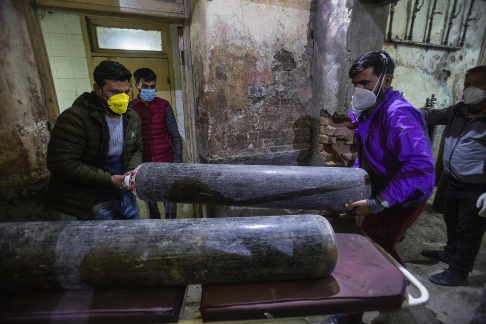 Attendants of a patient carry an oxygen cylinder for the patient inside a hospital in Srinagar, Indian controlled Kashmir, Sunday, April 25, 2021. India’s crematoriums and burial grounds are being overwhelmed by the devastating new surge of infections tearing through the populous country with terrifying speed, depleting the supply of life-saving oxygen to critical levels and leaving patients to die while waiting in line to see doctors. (AP Photo/Mukhtar Khan)