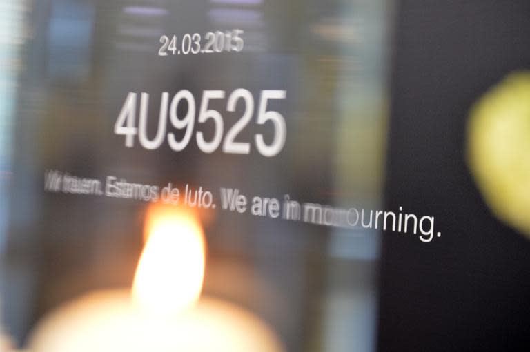 A candle is lit in front of a board with the flight number of Germanwings plane 4U92524 and the lettering 'We are in mourning' in English, German and Spanish at the Congress Center in Hamburg, on April 29, 2015