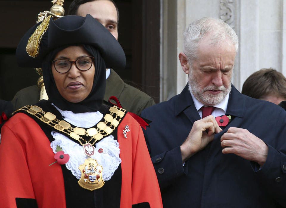 Britain's main opposition Labour Party leader Jeremy Corbyn adjusts his poppy, as he waits outside Islington Town Hall with Islington's Mayor Rakhia Ismail, ahead of observing a silence to mark Armistice Day, the anniversary of the end of the First World War, in London, Monday Nov. 11, 2019. Britain's Brexit is one of the main issues facing voters as political leaders tour the country ahead of a General Election on Dec. 12. (Jonathan Brady/PA via AP)