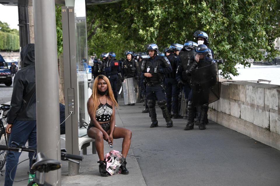 Image: Riot police officers stand next to a woman sitting at a bus stop in Paris (Anne-Christine Poujoulat / AFP via Getty Images file)
