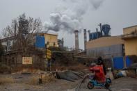 A woman rides a scooter past a steel plant in Anyang, Henan province, China, February 18, 2019. REUTERS/Thomas Peter