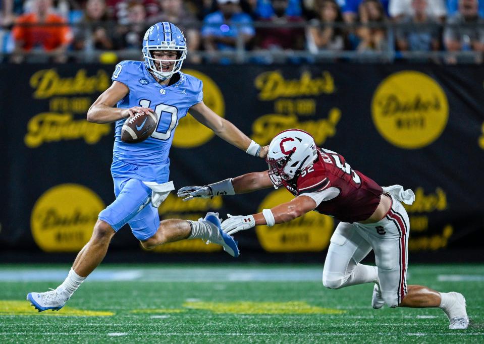 CHARLOTTE, NORTH CAROLINA - SEPTEMBER 02: Drake Maye #10 of the North Carolina Tar Heels stiff-arms Stone Blanton #52 of the South Carolina Gamecocks during the first half of the game at Bank of America Stadium on September 02, 2023 in Charlotte, North Carolina. (Photo by Grant Halverson/Getty Images)