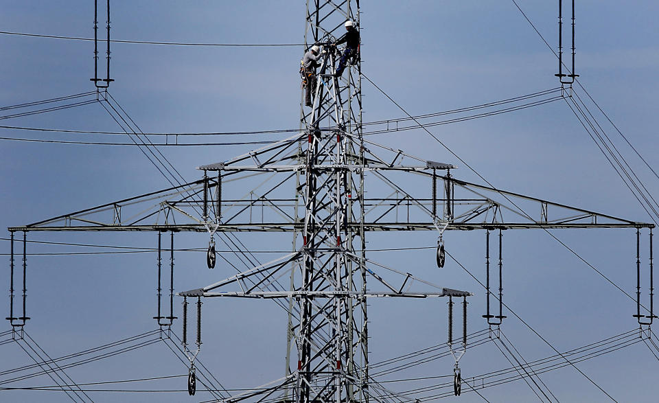 FILE - In this Monday, April 11, 2011 file photo, workers of the German energy company RWE prepare power supply on a high power pylon in Moers, Germany. Prices for electricity and natural gas are surging in Europe, raising concerns about politically unpopular increases in utility bills for consumers and even possible gas shortages when the weather gets colder. (AP Photo/Frank Augstein, File)