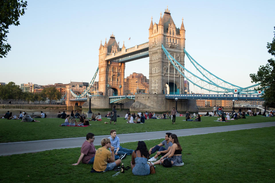 LONDON, Sept. 14, 2020  -- People sit on the lawn at Potters Fields Park in front of Tower Bridge in London, Britain, on Sept. 14, 2020.
  In order to curb the rise in coronavirus cases, tough new limits on social gatherings came into force in Britain on Monday, meaning that in most regions, it is now illegal for groups of more than six to meet up. The 