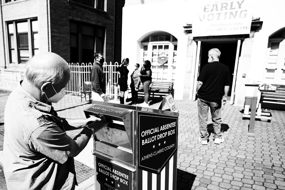 A voter drops their absentee ballot off at a drop box in Athens, Ga.