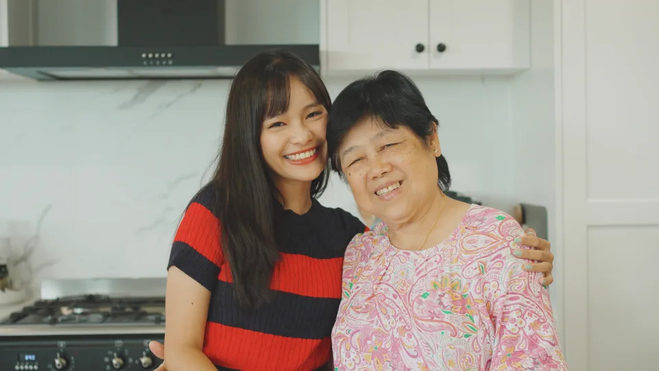 Portrait of happy and healthy young Asian woman and her mother in the kitchen, home insurance and wellness concept