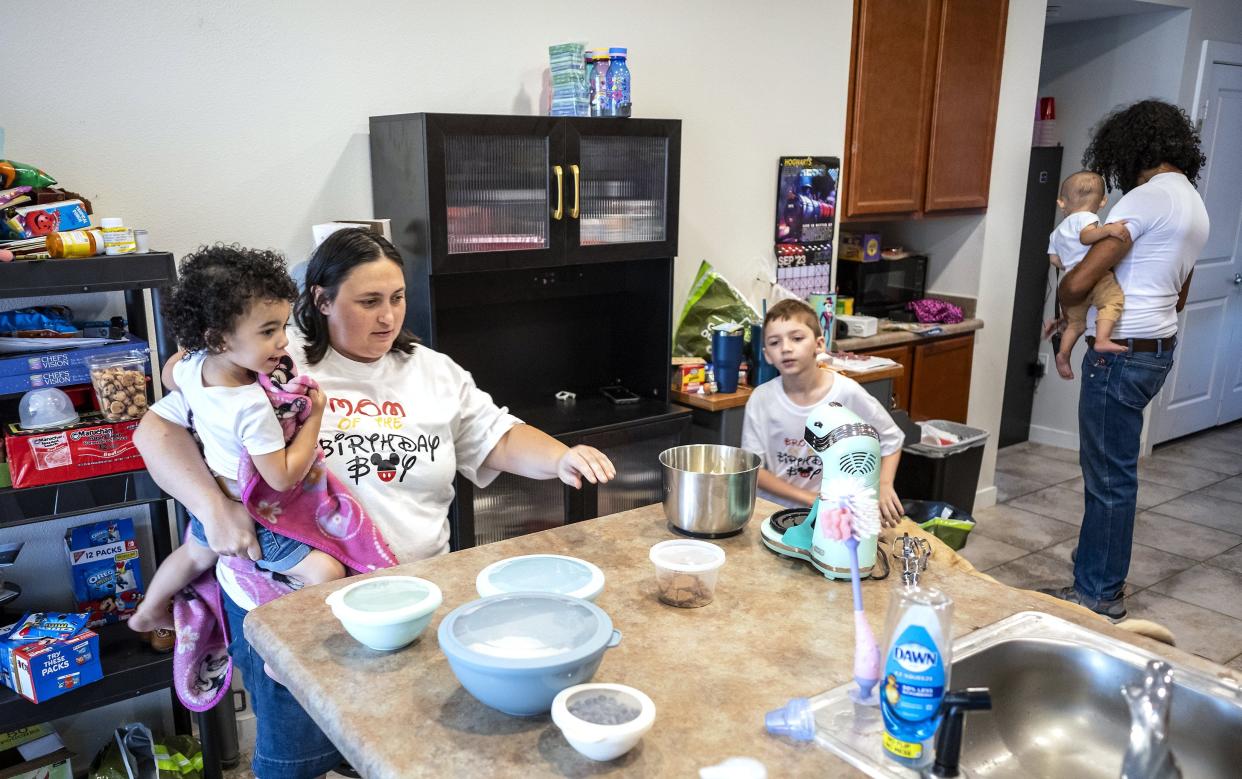 Rebecca Adamson, 31, with the help of Keiko, 2, and Leon, 8, makes a batch of chocolate cookies while Chris Watkins, 34, carries their son Lucas, 1. Adamson dreams of opening a bakery and joined the Marines to pay for culinary school. The family has struggled with homelessness.