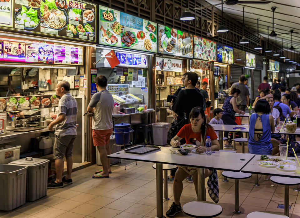 Locals and tourists, customers walking through and eating at the street hawker center in Telok Ayer Market, Singapore. To illustrate a piece in the Makan Index 2.0 survey.