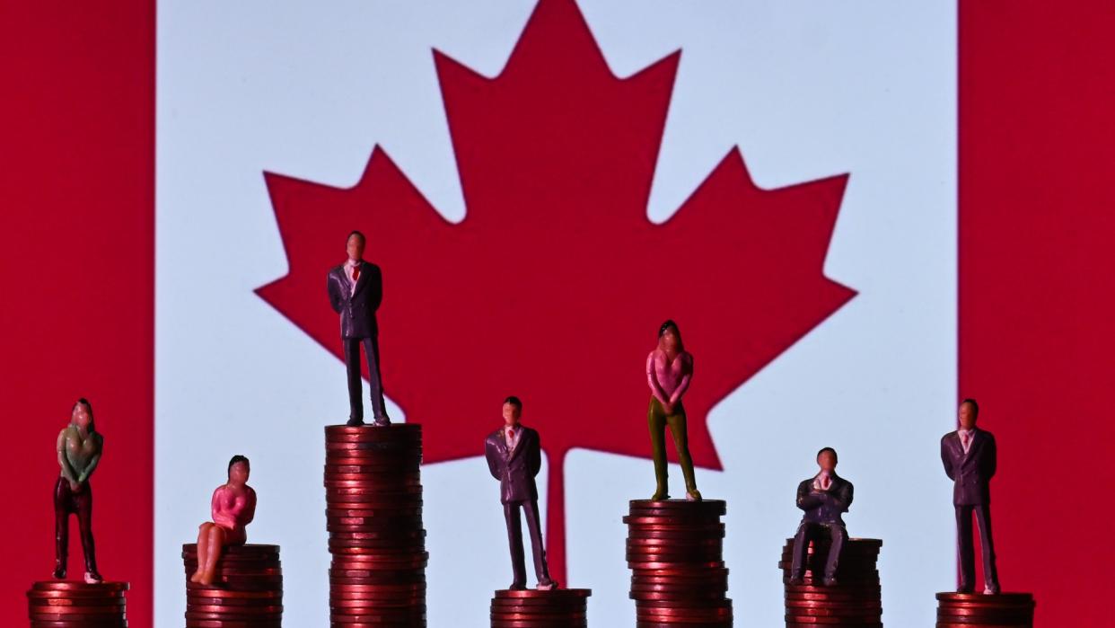  Illustrative photo showing small figures standing on a stack of coins, with the Canadian flag in the background. 