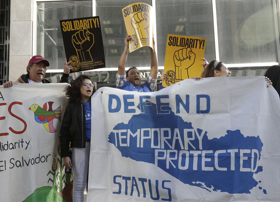FILE - In this Monday, March 12, 2018, file photo, supporters of temporary protected status immigrants hold signs and cheer at a rally before a news conference announcing a lawsuit against the Trump administration over its decision to end a program that lets immigrants live and work legally in the United States outside of a federal courthouse in San Francisco. A judge on Wednesday, Oct. 3, 2018, blocked the Trump administration from ending protections that let immigrants from four countries live and work legally in the United States, saying the move would cause "irreparable harm and great hardship." (AP Photo/Jeff Chiu, File)
