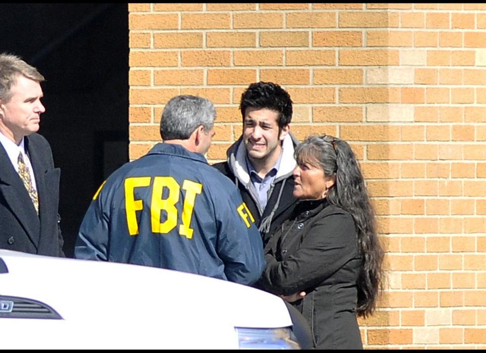 A FBI agent speaks with people in front of Chardon High School where a shooting took place on Feb. 27, 2012. A gunman, believed to be a student, opened fire inside the high school cafeteria, immediately killing three students and wounding two others.