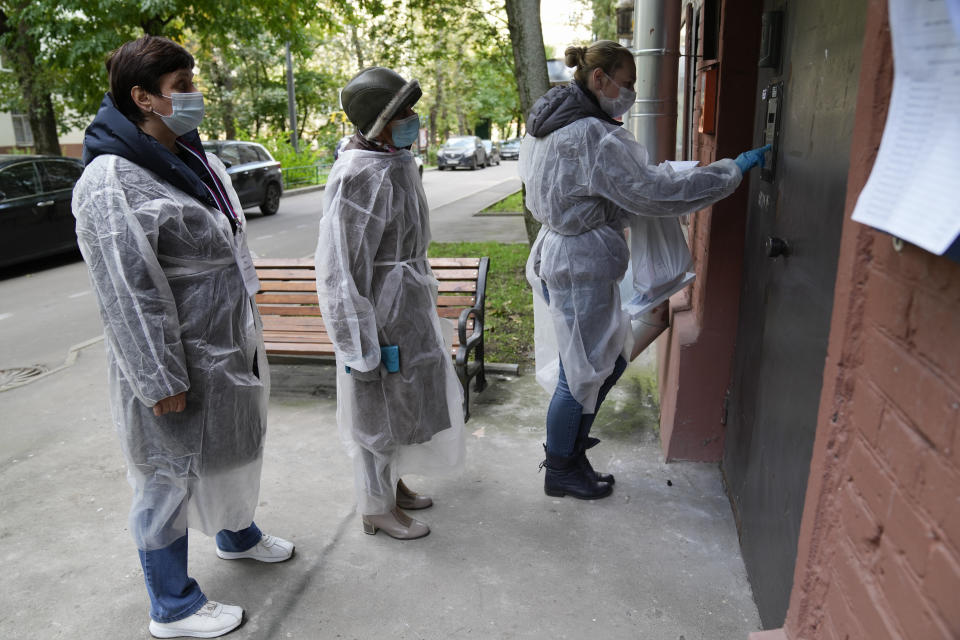 Members of an election commission, wearing gear to protect against coronavirus, enter a residential building as they come to visit a voter who wanted to vote at home during a parliamentary elections in Moscow, Russia, Saturday, Sept. 18, 2021. Sunday, Sept.19 will be the last of three days voting for a new parliament, but there seems to be no expectation that United Russia, the party devoted to President Vladimir Putin, will lose its dominance in the State Duma. (AP Photo/Pavel Golovkin)