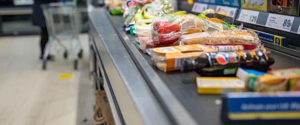 Groceries shopping at Lidl, checkout cashier counter belt full of groceries at supermarket. Shopping with social distancing measures in stores. SWANSEA, UK - MARCH 31, 2021