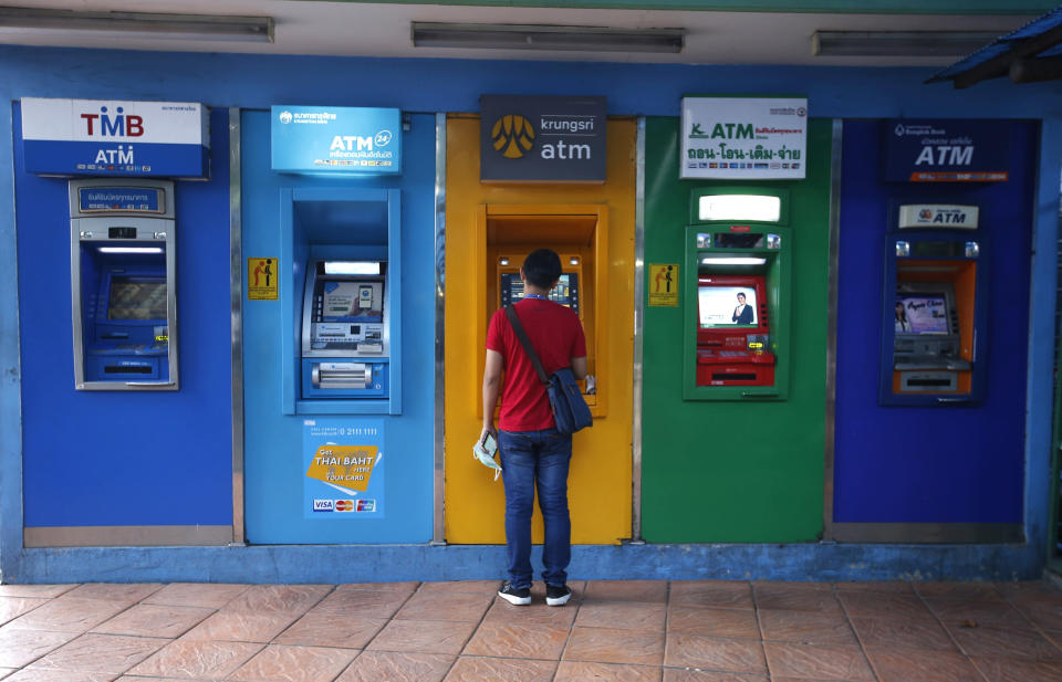 A Thai man withdraw money from automated teller machine Bangkok, Thailand Thursday, March 28, 2019. As Thais wait for official results of their general election, political parties led by one ousted from power in a military coup say they believe they have won enough seats to form the next government.(AP Photo/Sakchai Lalit)