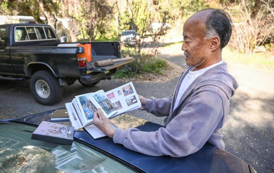 Chris Nishimura looks over a photo album of memories from his time working in Yosemite National Park and living in the El Portal Trailer Park on Sunday, March 13, 2022.