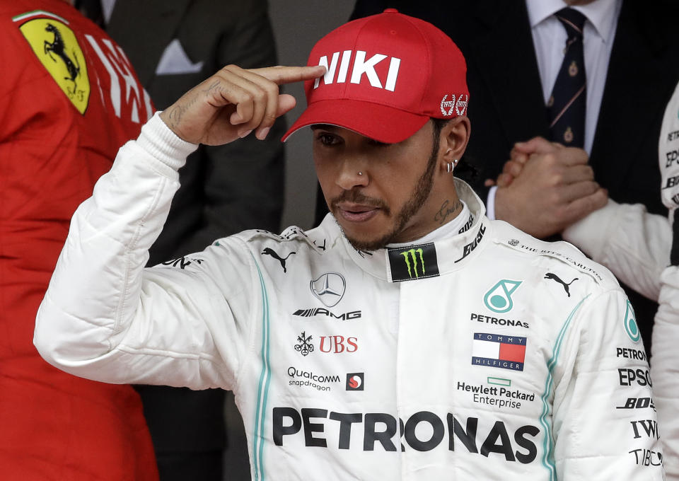 Mercedes driver Lewis Hamilton of Britain, center, points to his hat to tribute Niki Lauda after he won the Monaco Formula One Grand Prix race, at the Monaco racetrack, in Monaco, Sunday, May 26, 2019. (AP Photo/Luca Bruno)