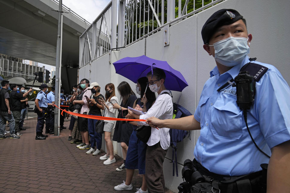 Police get people, including journalists, together to check IDs outside a court in Hong Kong, Saturday, June 19, 2021. A Hong Kong court ordered the top editor of pro-democracy newspaper Apple Daily and the head of its parent company held without bail Saturday in the first hearing since their arrest two days ago under the city's national security law. (AP Photo/Kin Cheung)