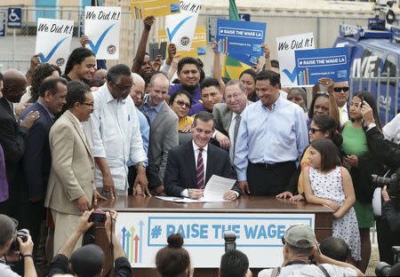 Los Angeles Mayor Eric Garcetti signs an ordinance raising the city's minimum wage to $15 an hour by 2020 from the current $9 in Los Angeles, California June 13, 2015. REUTERS/Jonathan Alcorn