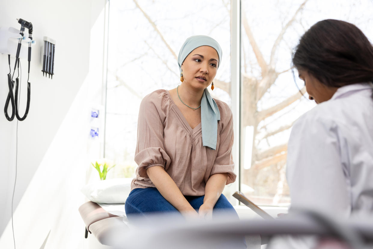 A woman sitting on an exam table speaking with a medical professional.