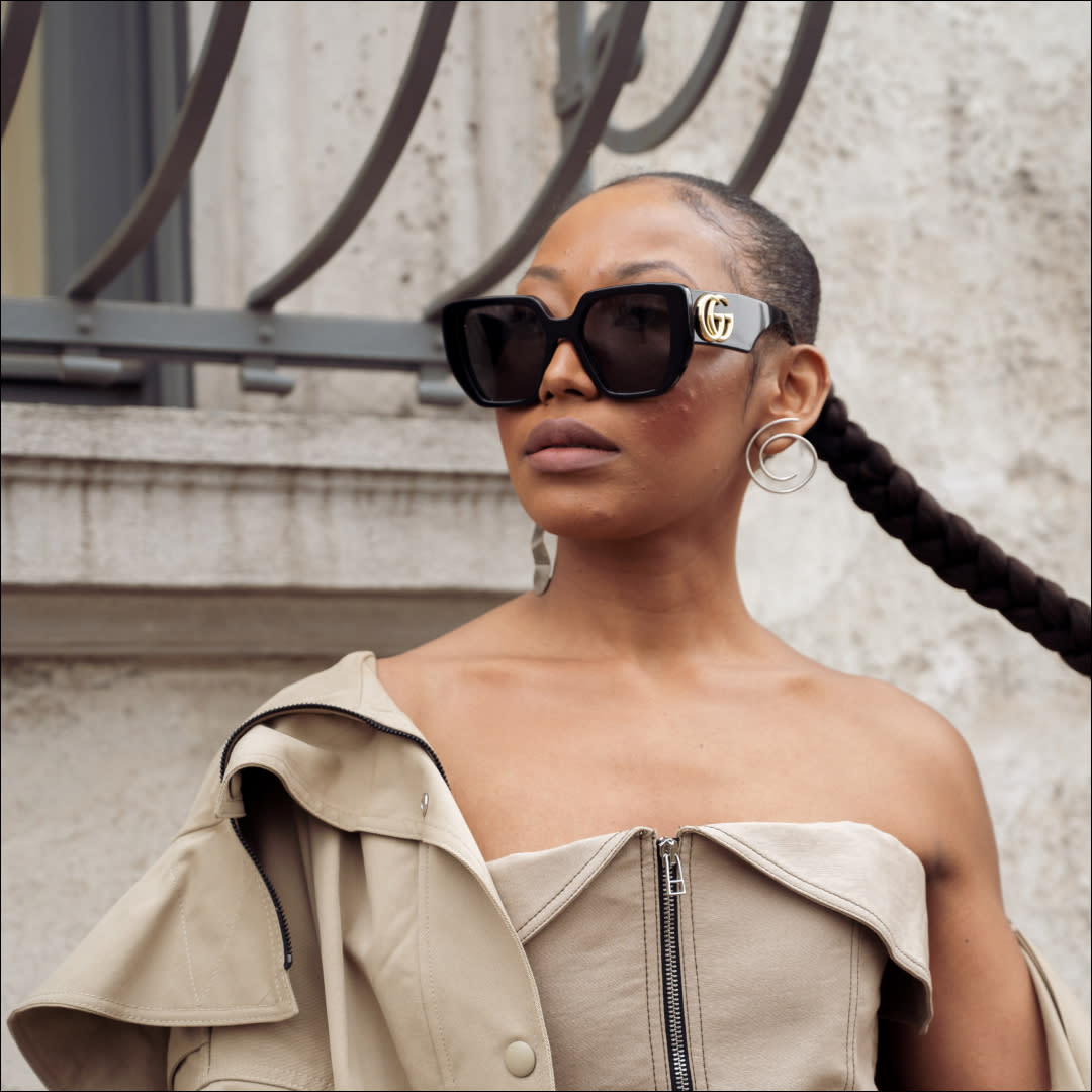  A guest wears beige pants, beige top and a jacket, white shoes, black bag and sunglasses outside the Prada show during the Milan Fashion Week Womenswear Fall/Winter 2023/2024 on February 23, 2023 in Milan, Italy.  