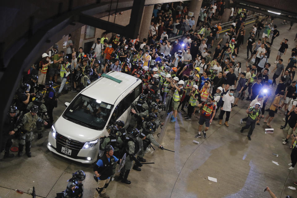 Police protect a police vehicle in Wong Tai Sin district in Hong Kong on Saturday, Aug. 3, 2019. Protesters and authorities clashed in Hong Kong again on Saturday, as demonstrators removed a Chinese national flag from its pole and flung it into the city's iconic Victoria Harbour and police fired tear gas after some protesters vandalized a police station. (AP Photo/Kin Cheung)