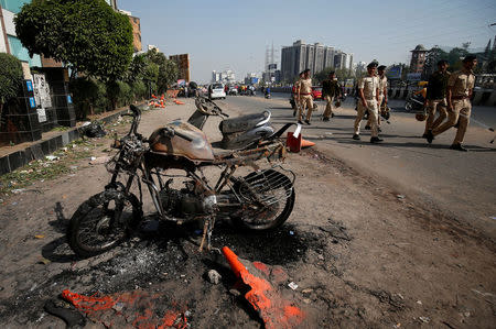 Policemen patrol a street next to a burnt motor bike, which was set on fire Tuesday night, following a protest by people, belonging to Rajput community, against the release of the upcoming Bollywood movie "Padmaavat", outside a multiplex in Ahmedabad, India January 24, 2018. REUTERS/Amit Dave